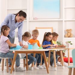 Nursery,Teacher,With,Group,Of,Cute,Little,Children,Drawing,And